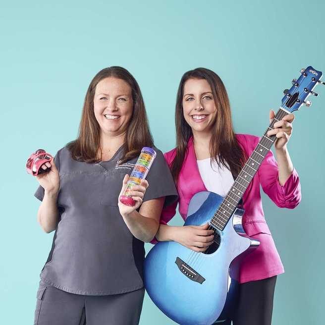 Two staff members with musical instruments, smiling.