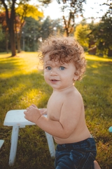 One year old baby boy posing with small white table