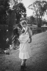 Mom and baby boy smiling and posing by a river