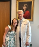 Addison stands with her surgeon Dr. Adzick in front of a portrait of Lori Howell