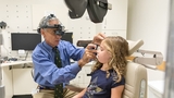 Doctor checking patient's eye in exam room