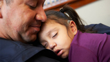 father holding sleeping daughter