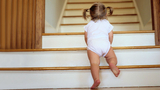 Infant girl climbing staircase