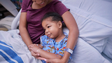 Mother holding daughter in hospital bed