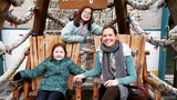 Julia and Claire with mom sitting at the Blue Cross River rink Winterfest