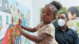 Little girl looking at the mural art