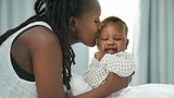 Mommy kissing baby on bed