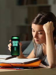 Young girl studying drinking an energy drink