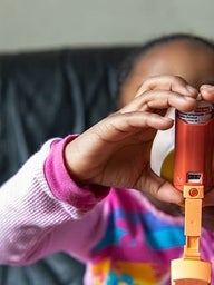 Child using inhaler with help of adult