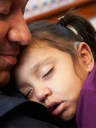 father holding sleeping daughter