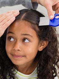 Young girl getting hair combed for lice test