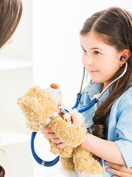 Young girl holding teddy bear and stethoscope