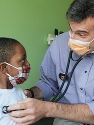 Doctor listening to young boy's heartbeat