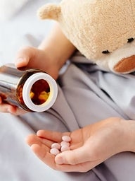 Patient's hand holding pills and bottle