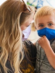 Mom holding son, both in masks