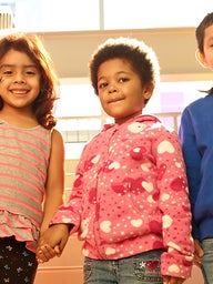 three children holding hands and smiling