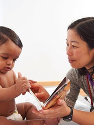 Elena Huang, M.D., a pediatrician at the Nicholas and Athena Karabots Pediatric Care Center, shares a book with Waldis, 8 months, as part of CHOP’s Reach Out and Read program.