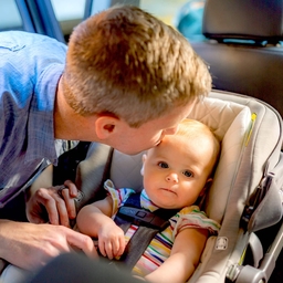 Father placing baby in car seat