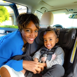 Mother placing child in car seat