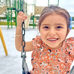 Lilliana smiling while riding a swing