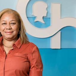 Woman in pink shirt with CH logo on blue wall