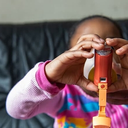 Child using inhaler with help of adult