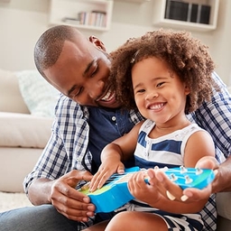 Father helping young daughter play ukulele