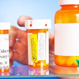 Hand reaching into medicine cabinet with pill bottles