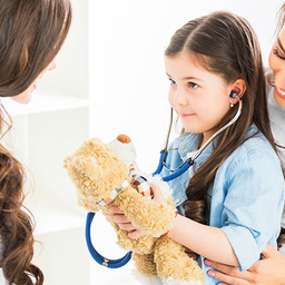 Young girl holding teddy bear and stethoscope