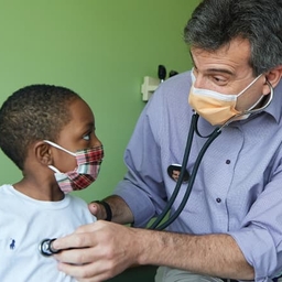 Doctor listening to young boy's heartbeat