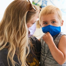 Mom holding son, both in masks