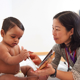 Elena Huang, M.D., a pediatrician at the Nicholas and Athena Karabots Pediatric Care Center, shares a book with Waldis, 8 months, as part of CHOP’s Reach Out and Read program.