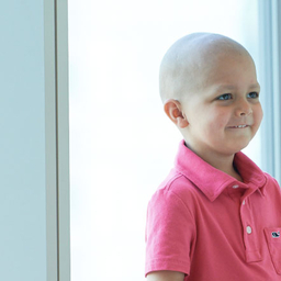 Young boy cancer patient sitting in hospital window smiling