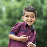 Smiling Hispanic boy wearing a purple shirt in the hospital garden