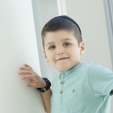 Smiling Jewish boy with green eyes and wearing a blue shirt