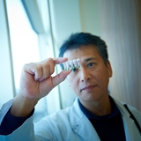 Researcher viewing a sample in a vial