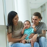 Smiling family of three, sitting in a hospital hallway