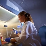 Lab technician working with smaples under protective hood