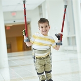 Boy smiling holding up his crutches wearing stiped tshirt.