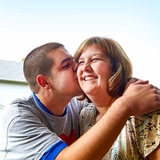 Son hugging his mom and placing a kiss on her cheek