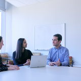 Three people sitting around a lap top